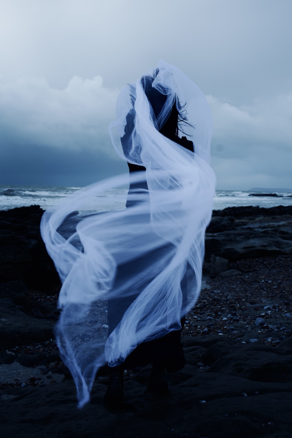 Dance with the Wind, figure entangled in translucent fabric by the sea