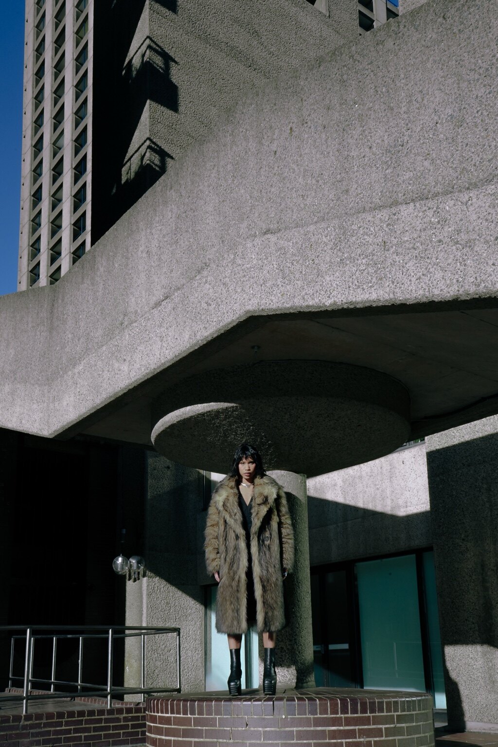 A figure standing beneath large concrete architecture in London